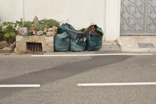 Workers loading bulky office furniture into a skip-style vehicle